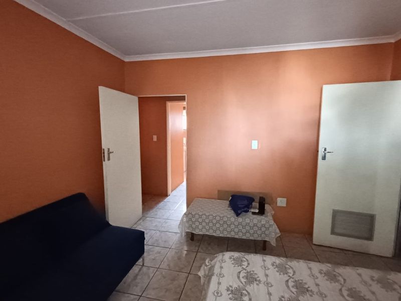 A bedroom featuring tiled flooring and standard internal doors, currently finished with orange wall paint.