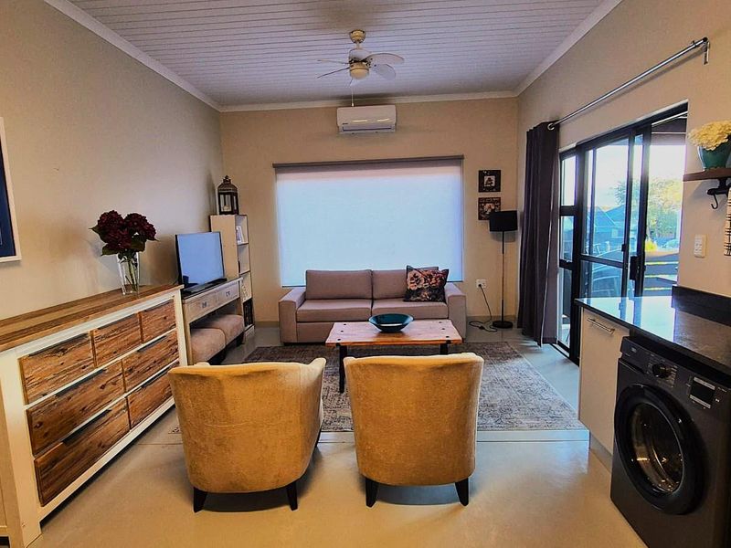 An open-plan living area featuring a modern kitchen corner with integrated laundry, split-system air conditioning, and sliding door access to the exterior.