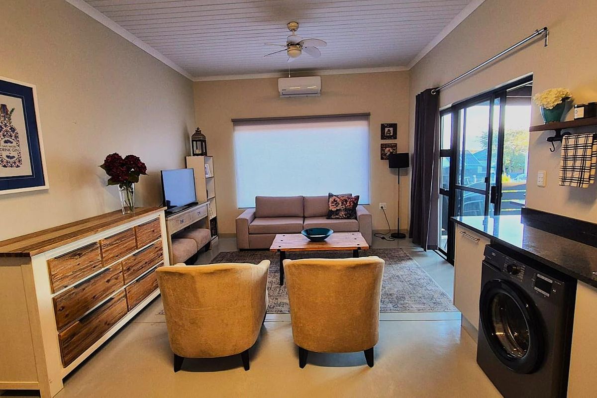 An open-plan living area featuring a modern kitchen corner with integrated laundry, split-system air conditioning, and sliding door access to the exterior.