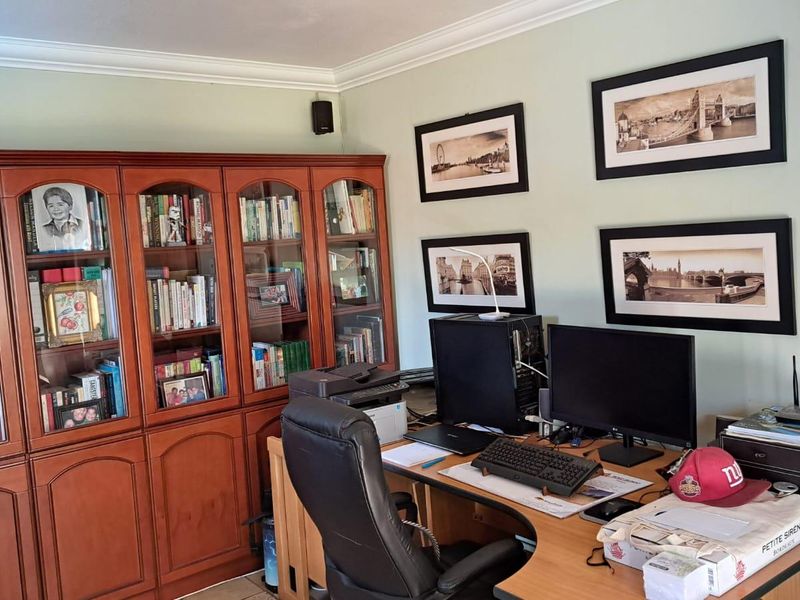 A home office featuring built-in wooden cabinetry and crown molding, providing a functional workspace with ample storage.