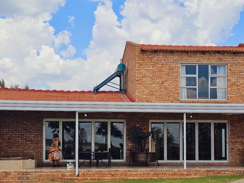 A well-maintained face-brick residence featuring a covered patio, large aluminium sliding doors, and a solar water heating system on the roof.