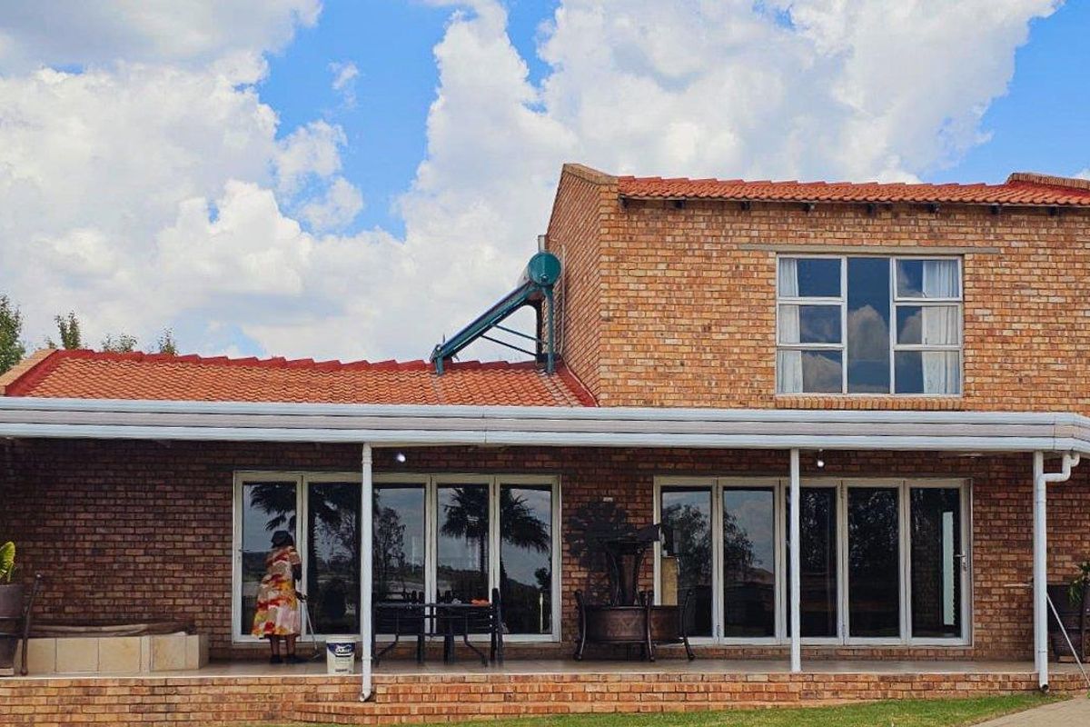 A well-maintained face-brick residence featuring a covered patio, large aluminium sliding doors, and a solar water heating system on the roof.