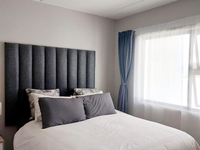 A well-maintained bedroom featuring neutral wall tones, tiled flooring, and a modern ceiling light fixture, providing a clean and comfortable living space.