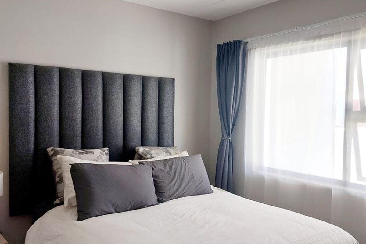A well-maintained bedroom featuring neutral wall tones, tiled flooring, and a modern ceiling light fixture, providing a clean and comfortable living space.