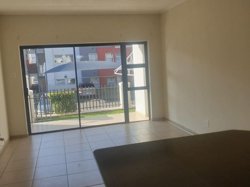 An open-plan living area featuring tiled flooring and a large sliding glass door that opens onto a private patio.