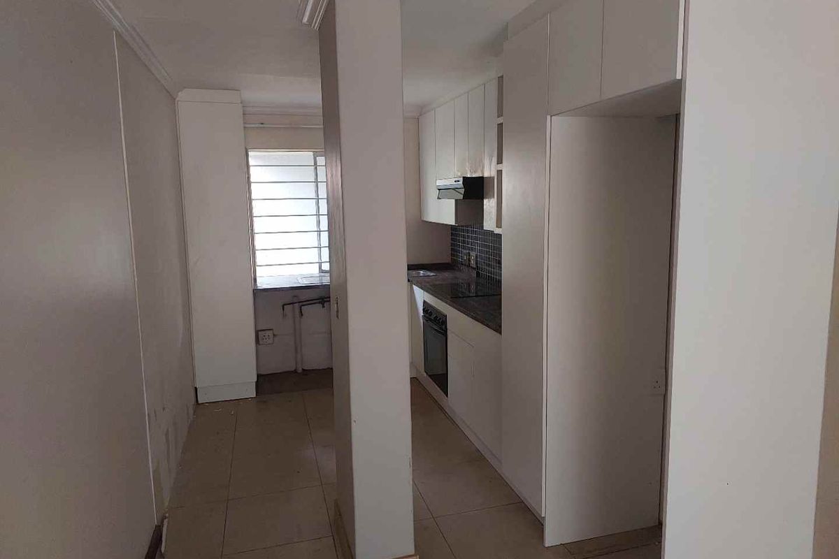 A functional kitchen featuring white built-in cabinetry, a tiled backsplash, and integrated appliances, offering a clean and practical layout for culinary activities.