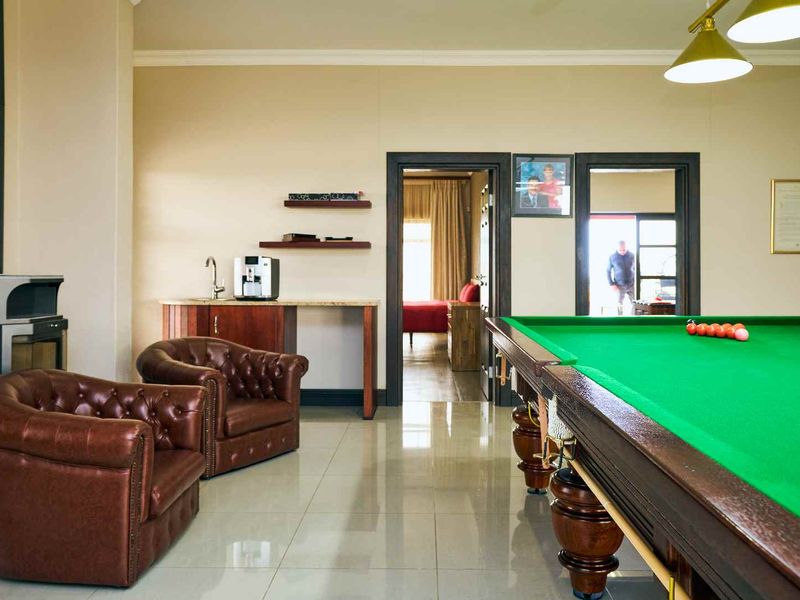 Spacious living area featuring a wood-burning fireplace, built-in bar counter, and polished tiled flooring, currently set up as a games room.