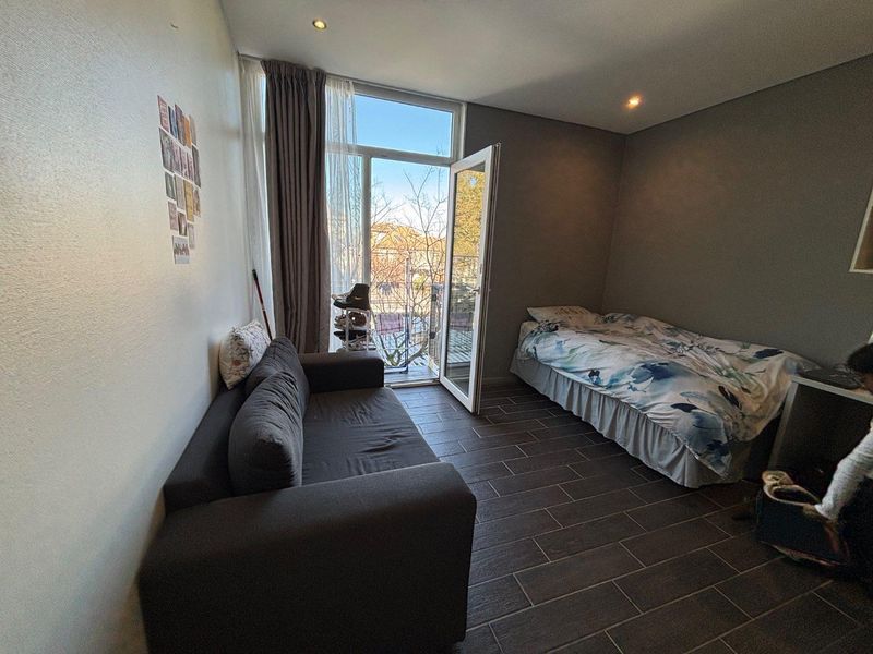 A bedroom featuring dark tiled flooring, recessed lighting, and direct access to a private balcony through a glass door.