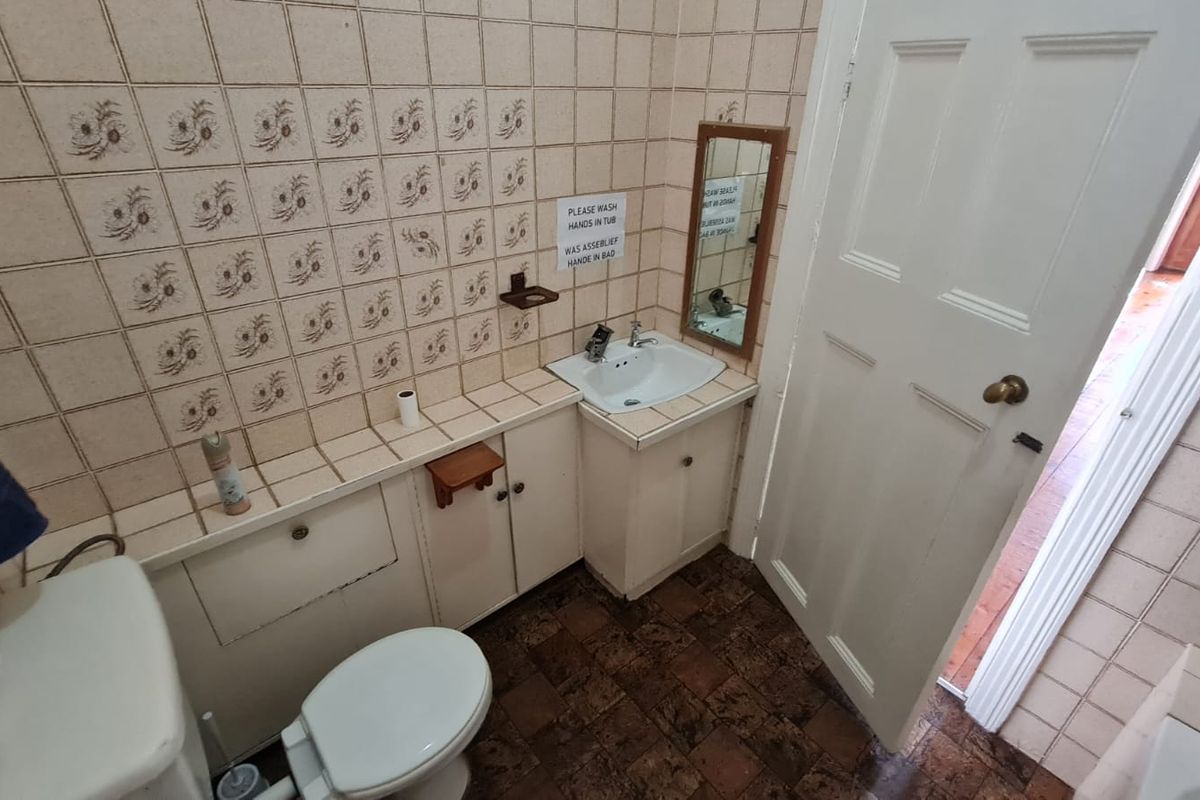 A compact bathroom featuring a built-in vanity with integrated sink, toilet, and dated decorative wall tiles.
