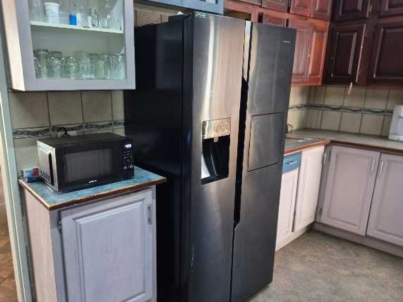 A functional kitchen featuring a mix of dark and light cabinetry, laminate countertops, and a tiled backsplash with a built-in refrigerator and microwave.