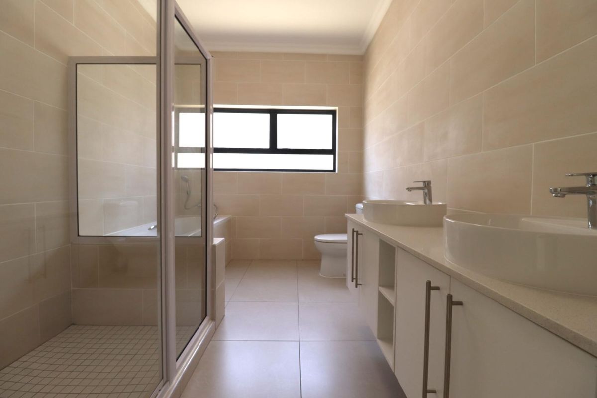 Modern bathroom featuring a glass-enclosed shower, a separate bathtub, and a double vanity with vessel sinks and contemporary cabinetry.