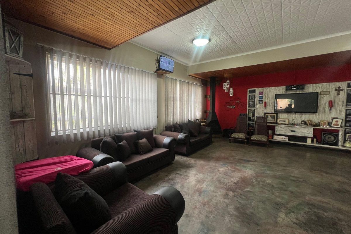 Spacious living room featuring a built-in fireplace, wood-paneled ceiling accents, and polished concrete flooring, offering a versatile layout for family relaxation.