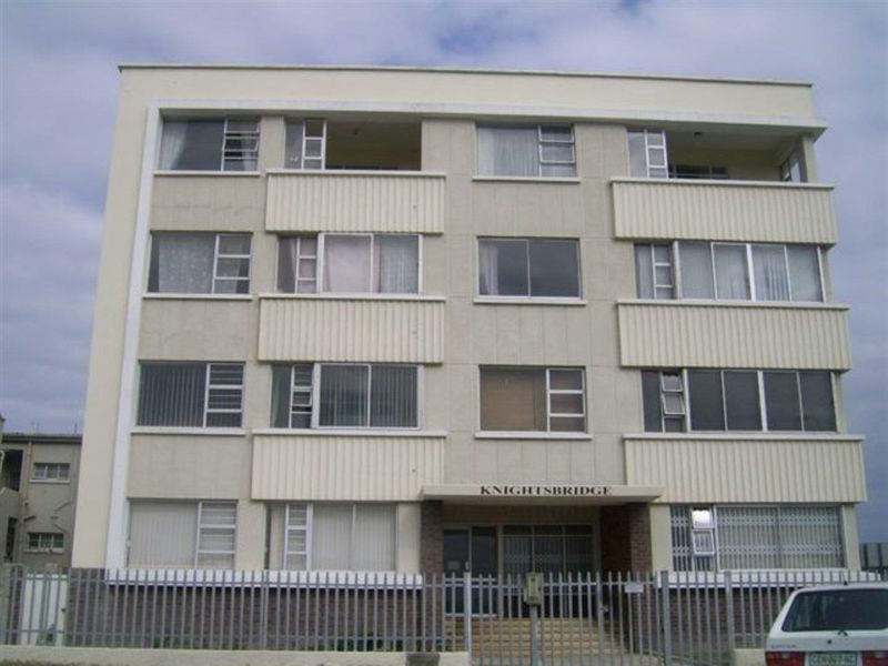 Front elevation of the Knightsbridge apartment building, featuring a multi-story facade with balconies, sliding windows, and secure perimeter fencing.