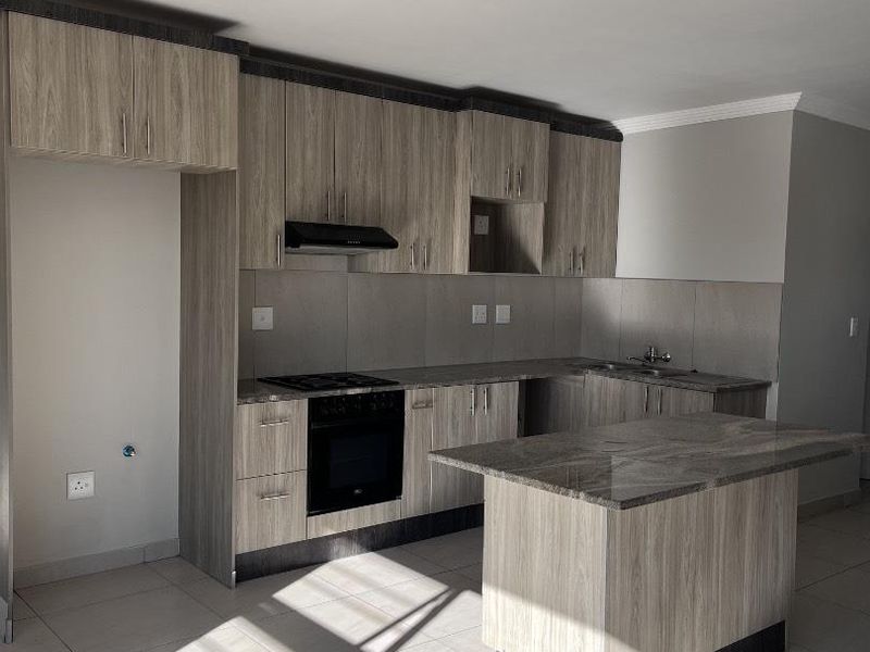 Modern kitchen featuring light wood-grain cabinetry, stone countertops, a central island, and integrated appliances including a gas hob and oven.