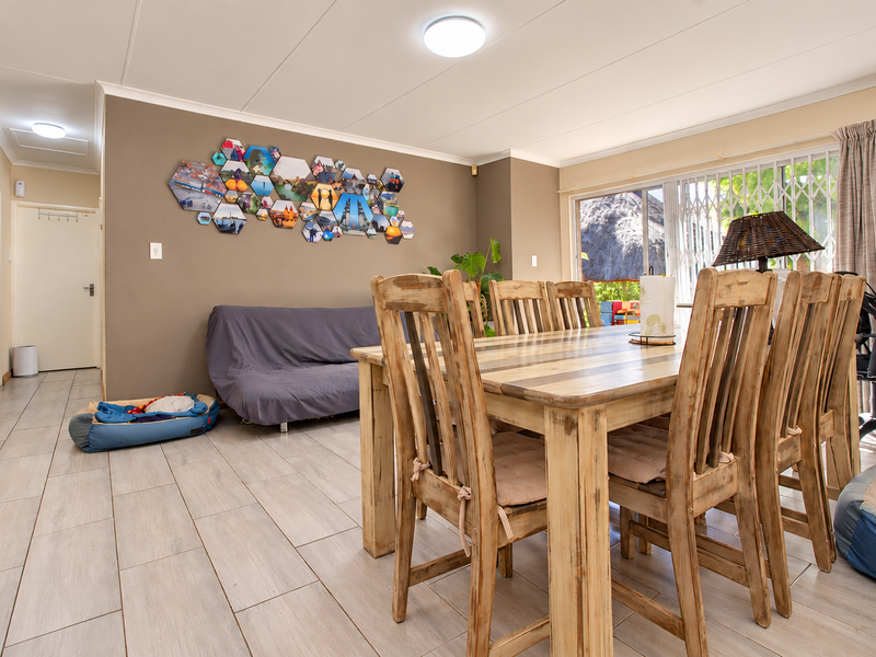A dining area featuring tiled flooring, neutral wall tones, and a sliding glass door providing access to the exterior.