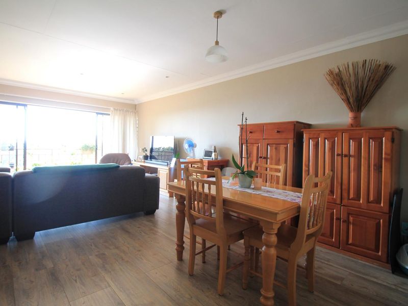 Spacious open-plan living and dining area featuring laminate flooring, recessed lighting, and large sliding glass doors providing ample natural light.
