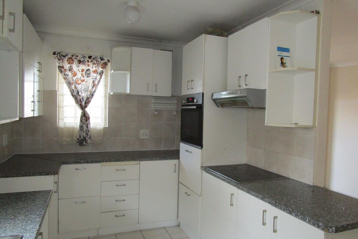A functional kitchen featuring white built-in cabinetry, granite-look laminate countertops, tiled backsplash, and integrated appliances including an oven, hob, and extractor fan.