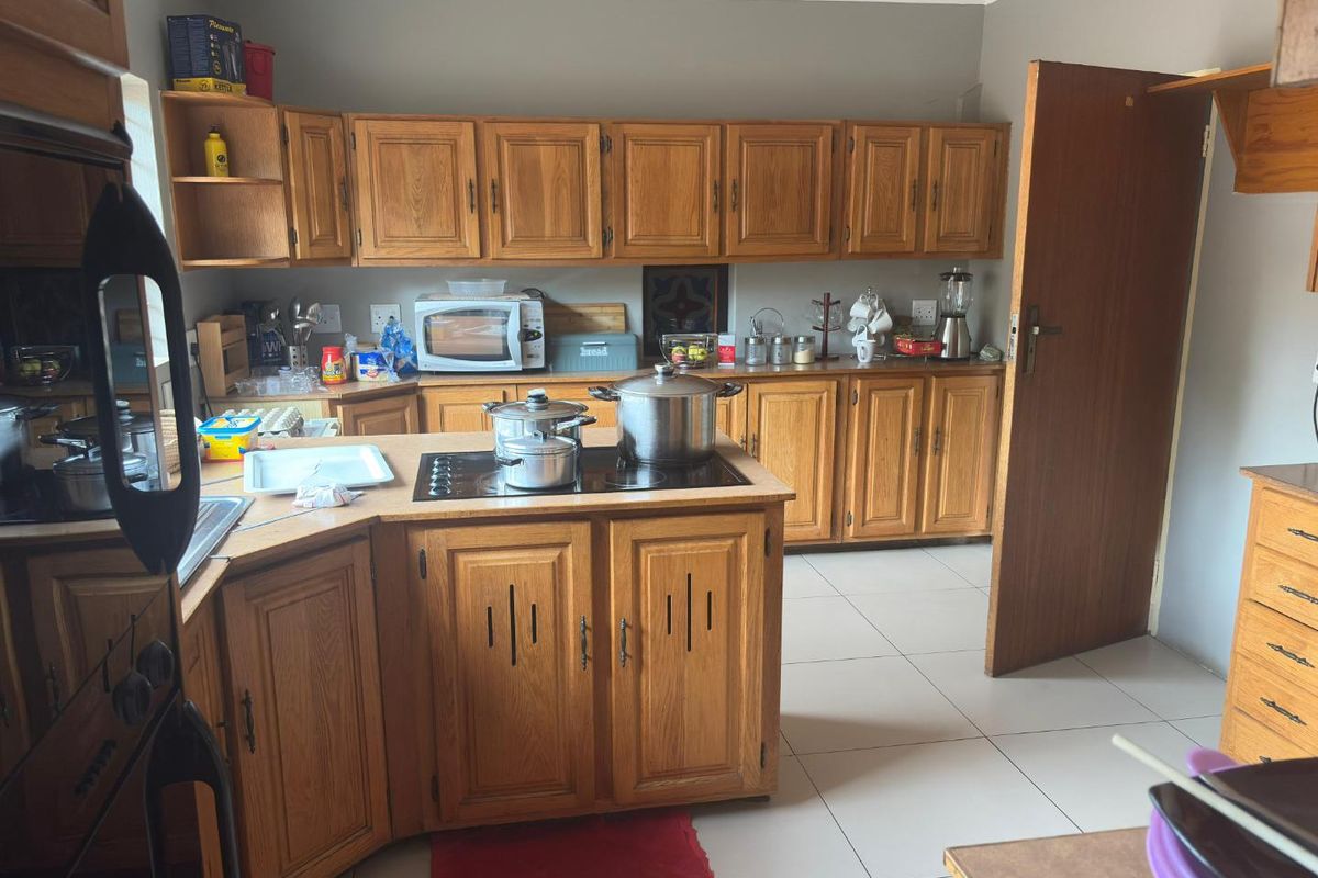 A functional kitchen featuring traditional wooden cabinetry, a central island with a built-in hob, and tiled flooring.