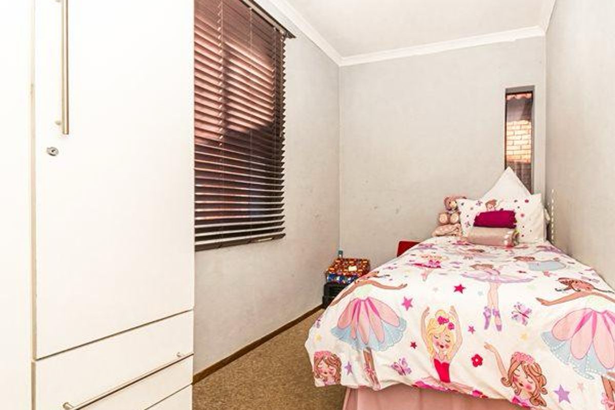A compact bedroom featuring built-in cabinetry, carpeted flooring, and a window fitted with horizontal blinds.