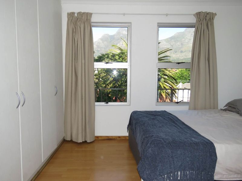Bedroom featuring built-in cupboards, laminate flooring, and dual windows offering scenic mountain views.