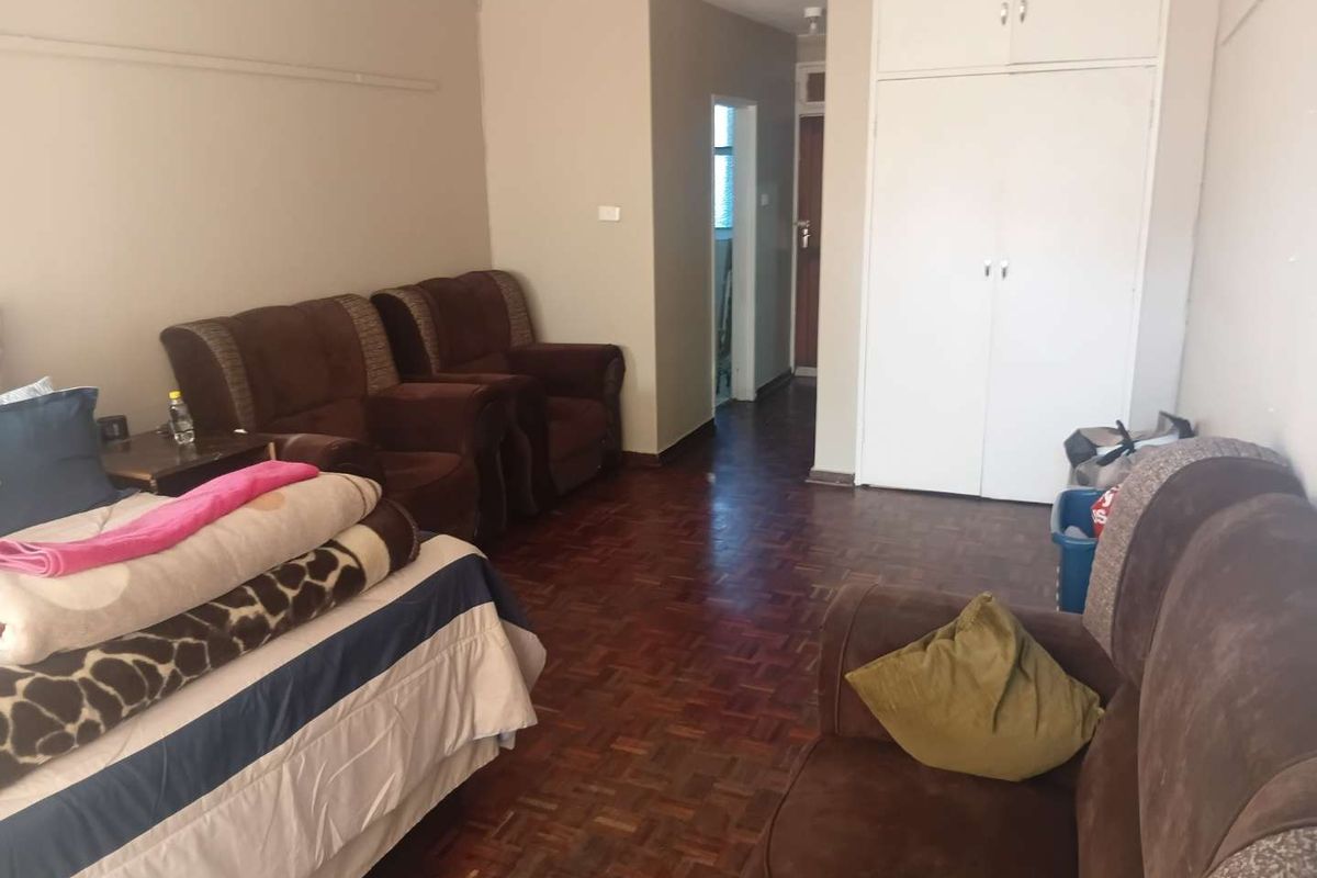 Living room featuring traditional parquet flooring and a built-in storage cupboard, offering a functional space with potential for cosmetic updates.
