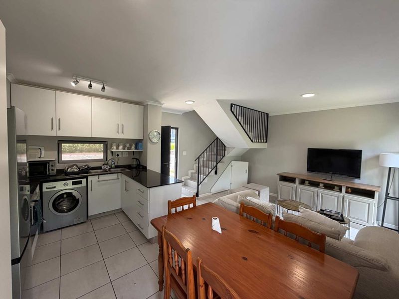 Open-plan living area featuring a modern kitchen with granite countertops, tiled flooring, and a staircase leading to the upper level.