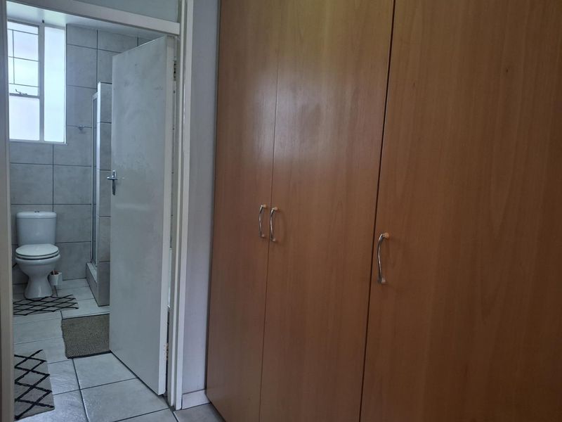 Bedroom featuring built-in wooden cupboards and direct access to an en-suite bathroom with tiled finishes.