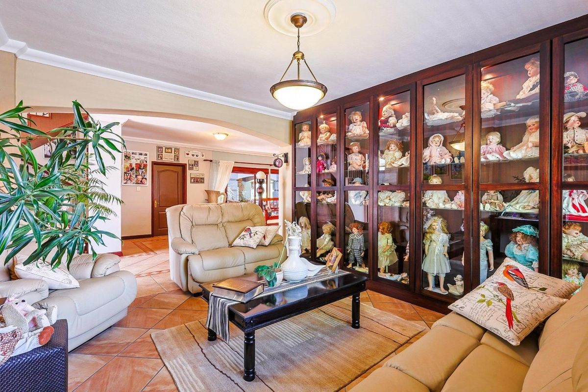 A spacious living room featuring large built-in wooden display cabinetry with glass doors, tiled flooring, and a central pendant light fixture.