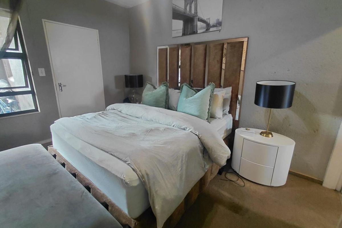 A bedroom featuring a large window, neutral wall tones, and carpeted flooring, providing a functional and comfortable sleeping space.