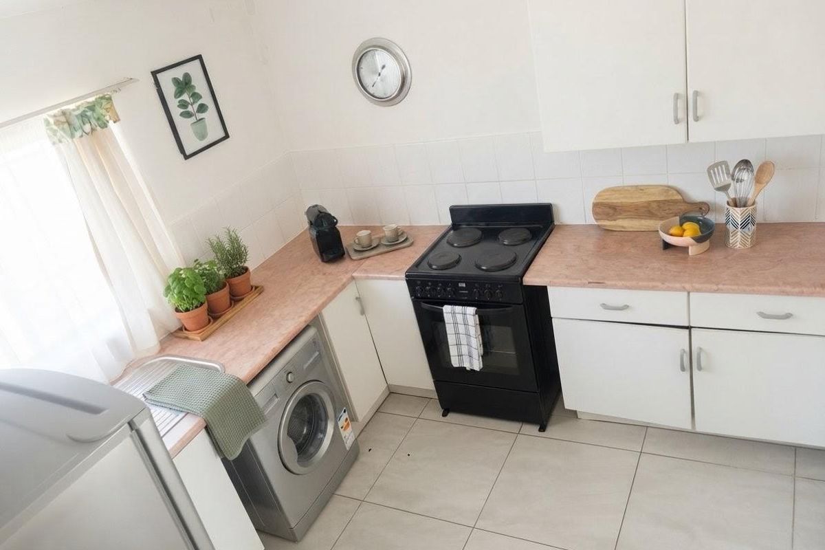 A functional kitchen featuring white cabinetry, laminate countertops, tiled backsplash, and ceramic floor tiles, providing a practical workspace for daily cooking needs.