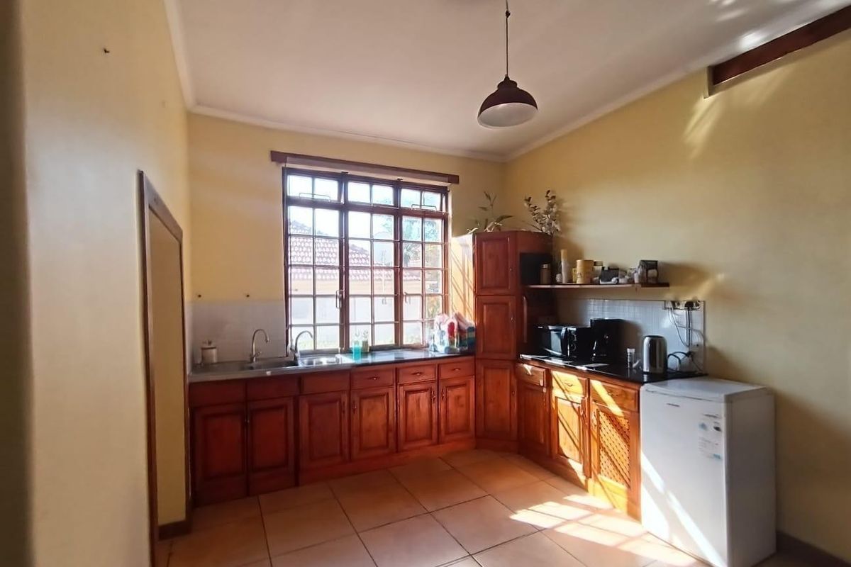 A functional kitchen featuring wooden cabinetry, tiled flooring, and a double basin sink, offering a classic layout with potential for modern updates.