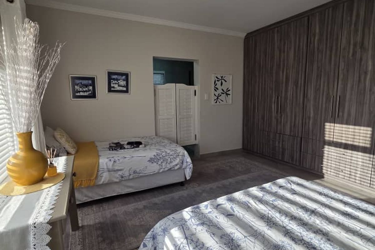 A well-maintained bedroom featuring extensive built-in wooden cabinetry, neutral wall finishes, and natural light filtering through window blinds.