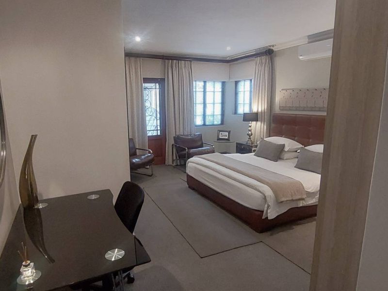 Spacious bedroom featuring neutral tones, carpeted flooring, recessed lighting, and a split-system air conditioner, with direct access to an outdoor area.