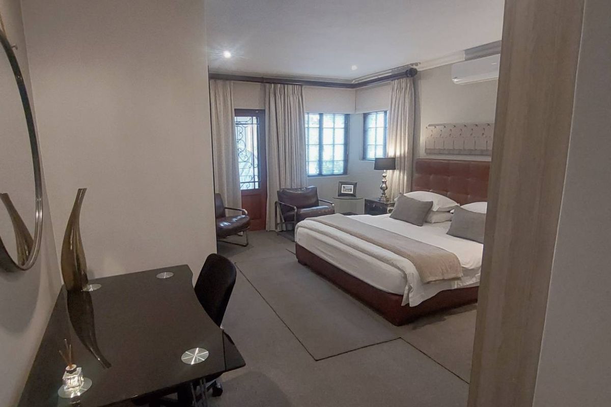 Spacious bedroom featuring neutral tones, carpeted flooring, recessed lighting, and a split-system air conditioner, with direct access to an outdoor area.