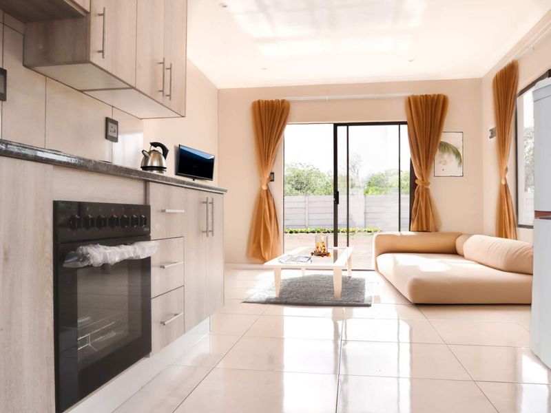 Modern open-plan living area featuring a contemporary kitchen with built-in cabinetry, oven, and seamless access to the outdoor patio through sliding glass doors.