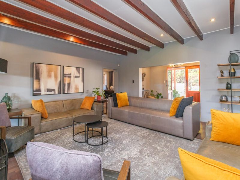 Spacious living room featuring exposed timber ceiling beams, recessed lighting, and a built-in shelving unit, creating a warm and inviting atmosphere.