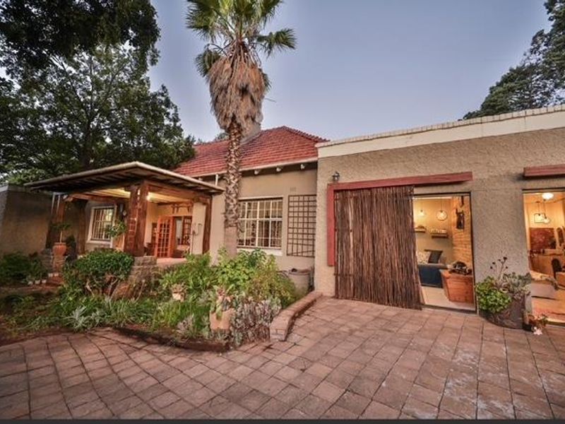 Rear exterior view featuring a paved patio area, timber pergola, and direct access to the interior through sliding glass doors.