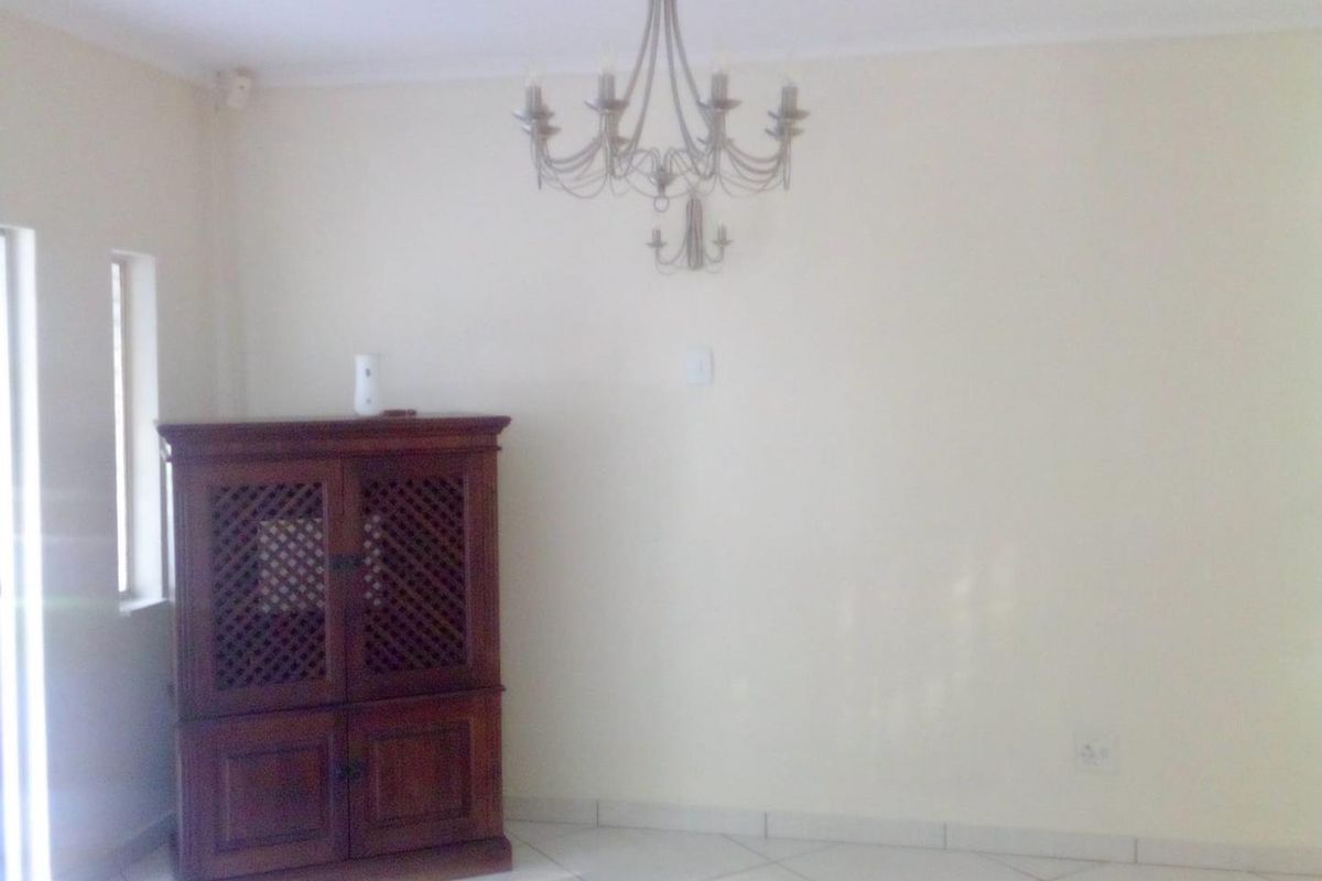 A bright living area featuring tiled flooring and a decorative chandelier, offering a neutral canvas for interior design.