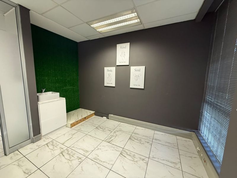 Office space featuring marble-look tiled flooring, a built-in vanity sink, drop ceiling with integrated lighting, and venetian blinds.