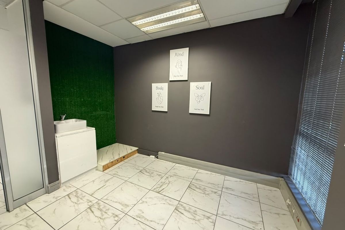 Office space featuring marble-look tiled flooring, a built-in vanity sink, drop ceiling with integrated lighting, and venetian blinds.