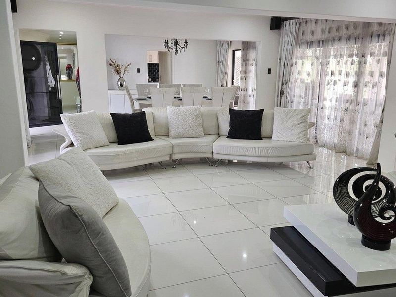 Spacious open-plan living and dining area featuring polished porcelain floor tiles, recessed lighting, and large sliding glass doors leading to the exterior.