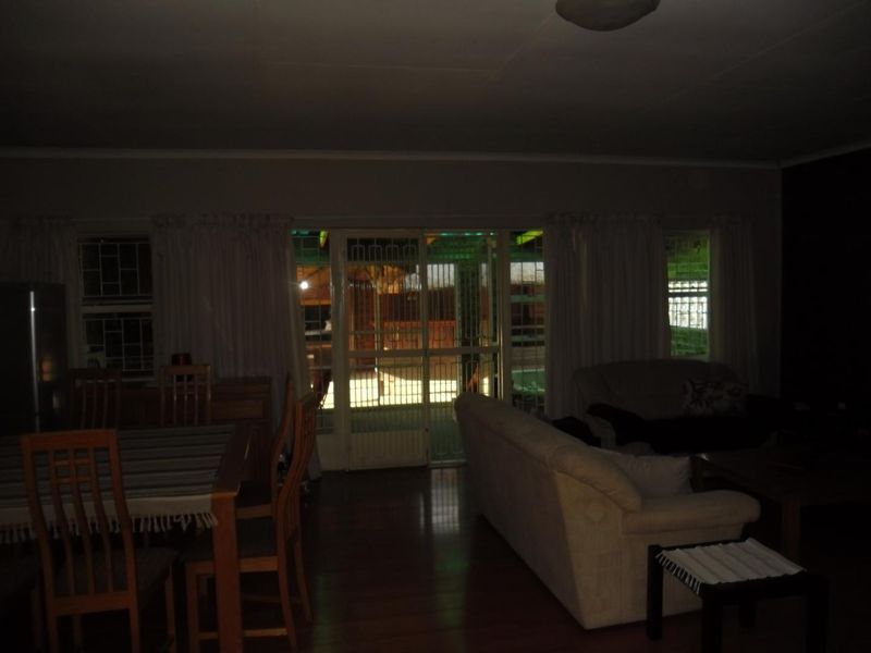 Open plan living and dining area featuring laminate flooring and direct access to the outdoor patio through a security gate and sliding glass door.