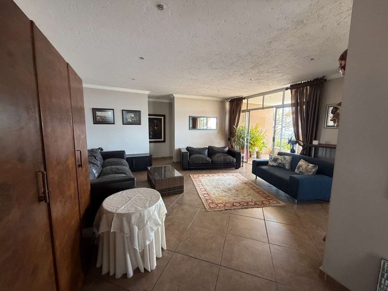 Spacious living room featuring large format floor tiles, recessed lighting, and sliding glass doors providing access to an outdoor patio area.