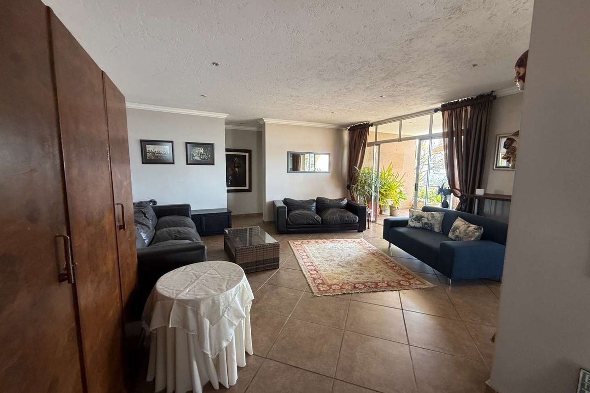 Spacious living room featuring large format floor tiles, recessed lighting, and sliding glass doors providing access to an outdoor patio area.