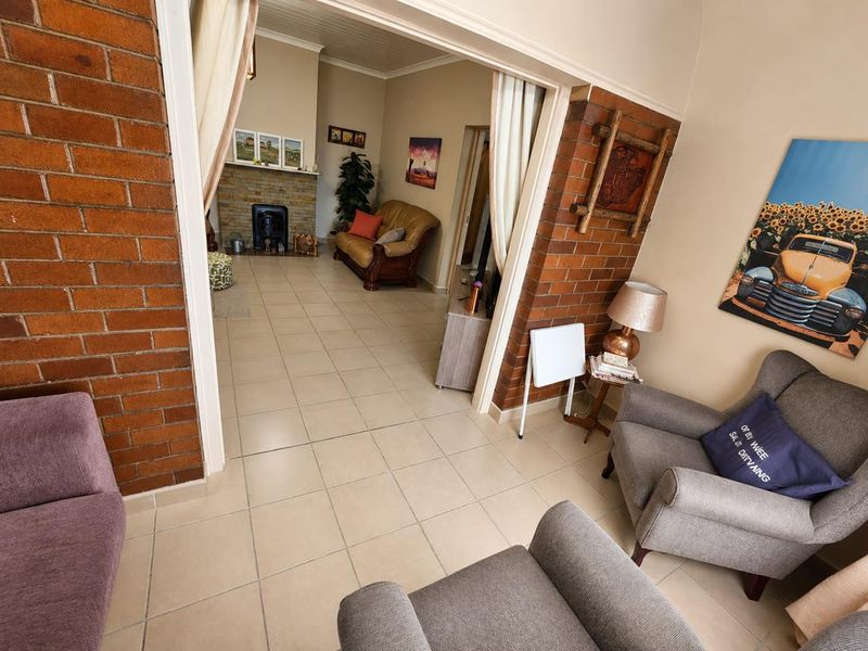A spacious living area featuring exposed brick walls, tiled flooring, and a fireplace, creating a warm and inviting atmosphere.