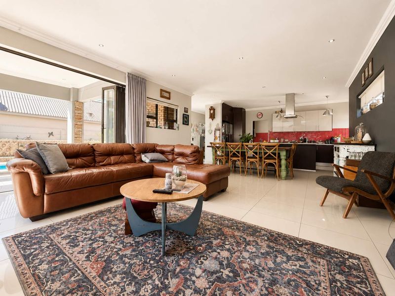 Spacious open-plan living area featuring tiled floors, recessed lighting, and a modern kitchen with a central island and red tiled backsplash.