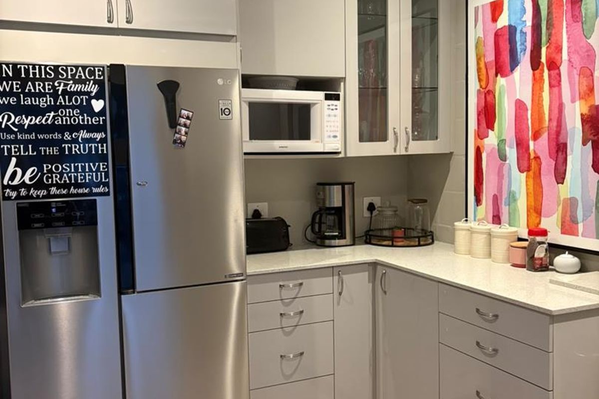 A modern kitchen area featuring light grey cabinetry, stone countertops, and a built-in microwave, providing a clean and functional workspace.