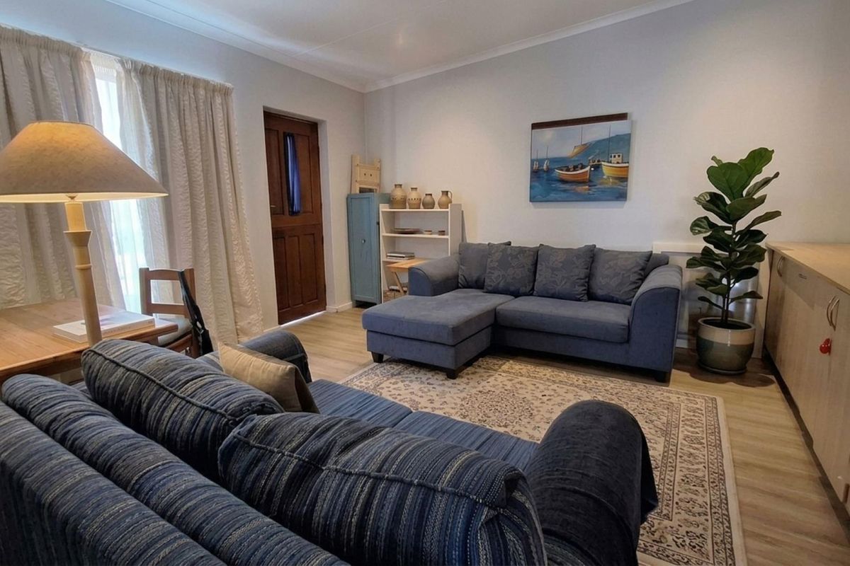 A comfortable living room featuring light-toned laminate flooring, neutral walls, and built-in storage cabinetry along the wall.