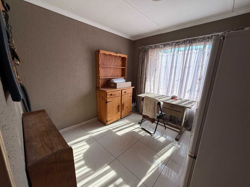 A functional dining area featuring neutral tiled flooring and natural light from a large window.