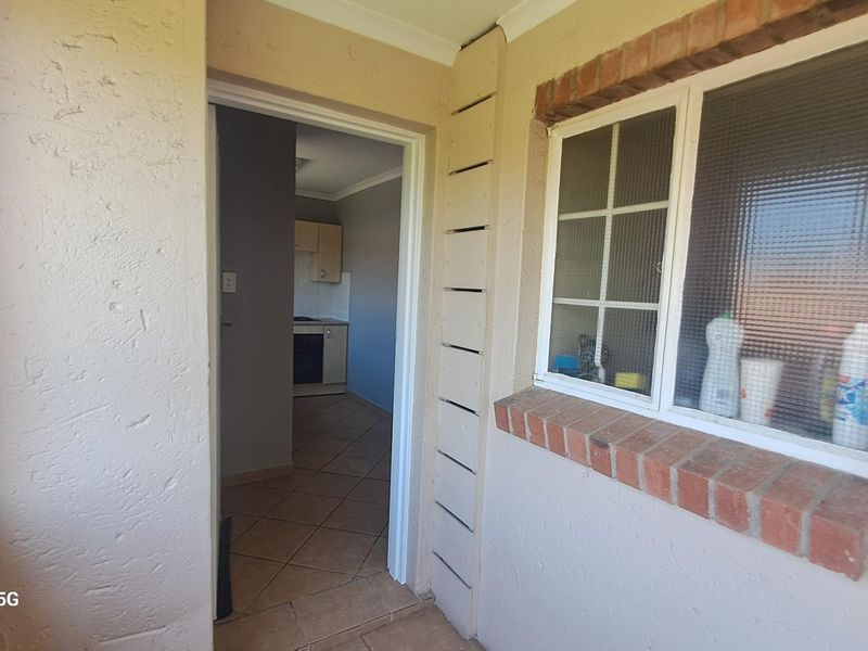 Exterior entrance area featuring brick detailing and a window, providing a view into the interior kitchen space.